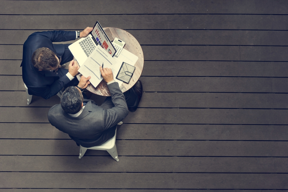 overhead shot of two business men sitting at a table reviewing documents