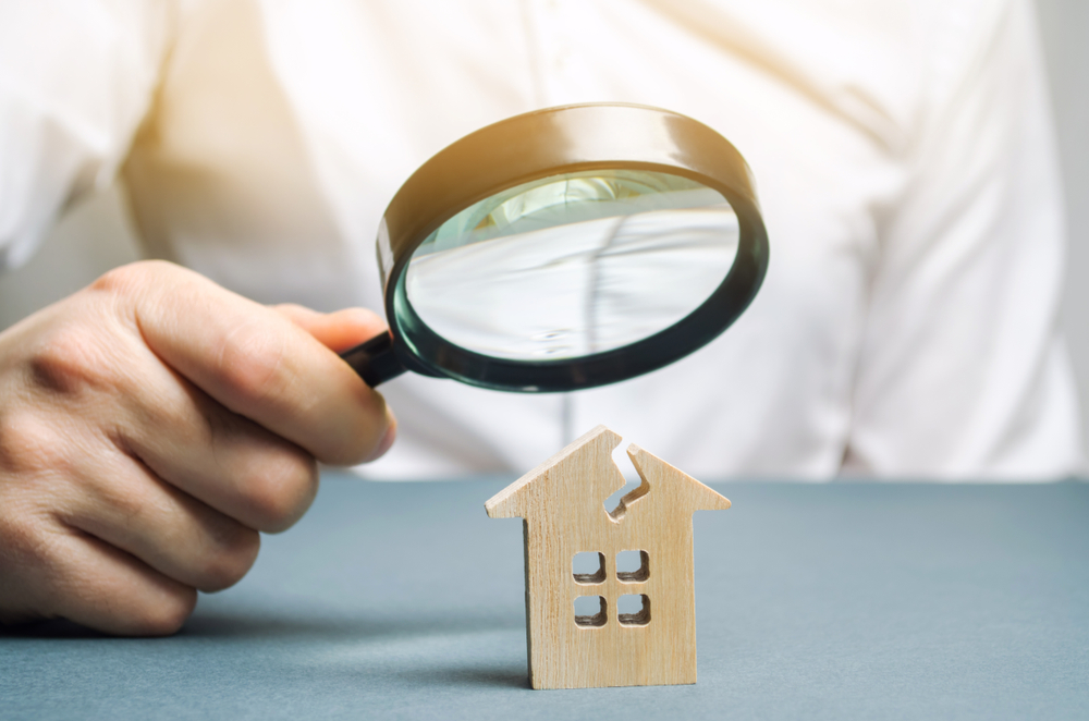 magnifying glass in hand over a small wooden house